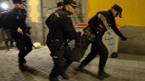 Spanish police run through the streets carrying a protester who fell down during a police charge in the Lavapies district