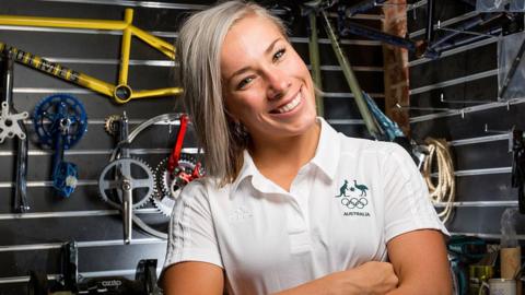 Caroline Buchanan wearing an Australian sports uniform in front of cycling gear