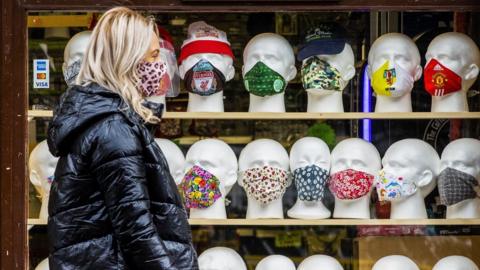 A woman walks past face coverings on display at a Belfast newsagent