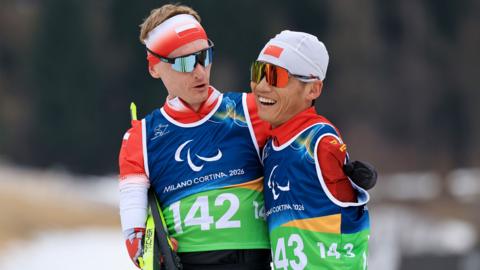 Witold Skupien of Team Poland and Chenyang Wang of Team People's Republic of China react after competing in the Men's 10km Para Cross-Country Skiing Standing during the on day five of the Milano Cortina 2026 Winter Paralympic Games at Tesero Cross-Country Skiing Stadium on March 11, 2026 in Val di Fiemme, Italy.