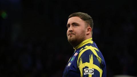 Stock image of Luke Littler. He is looking into the distance.