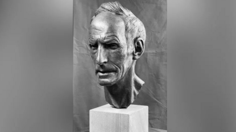 A black-and-white photo of the sculpture of Joss Naylor's head and neck. The face has a stern expression.