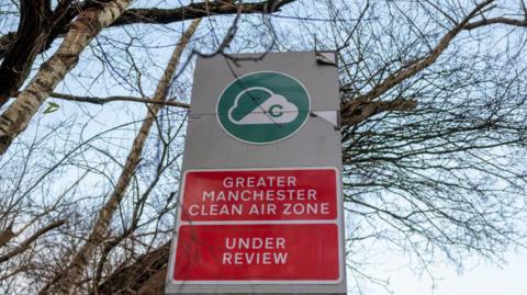 Large road sign advising motorists about Greater Manchester's plans for a clean air zone. The sign has previously been amended due to delays in the scheme's introduction