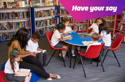 Children and a teacher sit around a table and on soft cushions reading books in a library. Text in the right hand corner reads "Have your say".