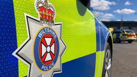 Generic shot of the side of a Wiltshire Police car. It is a close-up, showing the logo.