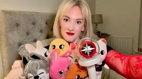 A blonde woman holding stuffed toys