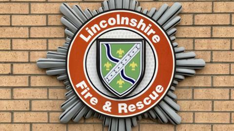 A close-up of Lincolnshire Fire and Rescue's logo, fixed to a brick wall.