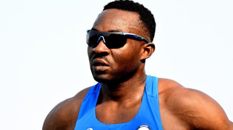 Guillaume Junior Atangana wearing a blue running vest and sunglasses