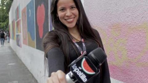 Ana Guaita Barreto holding a microphone with the logo of the news site she works for