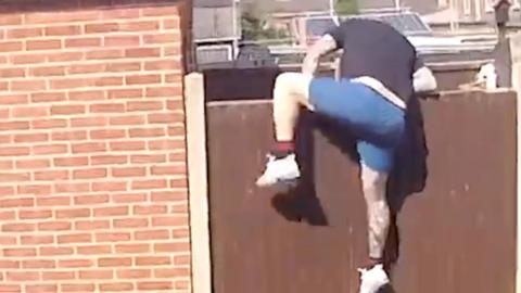 Man jumping over a garden fence.