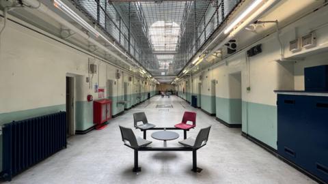 One of the wings inside the prison with seats and tables visible