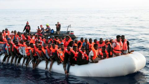 Migrants are seen in a rubber dinghy as they are rescued by the crew of the Mission Lifeline rescue boat in the central Mediterranean Sea, 22 June 2018