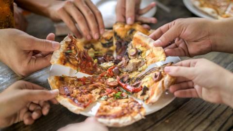 Generic pic of people helping themselves to pizza