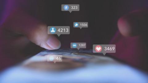Two thumbs scrolling down a social media feed on a phone screen with likes, comments, shares and follow graphics surrounding it