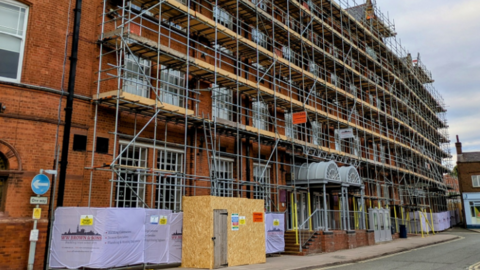 A large red-brick building covered in scaffolding