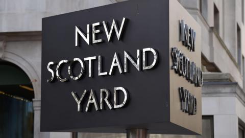 A sign saying New Scotland Yard in front of a white stone building.