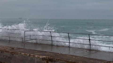 Waves crashing up onto the railings at St Ouen's bay.