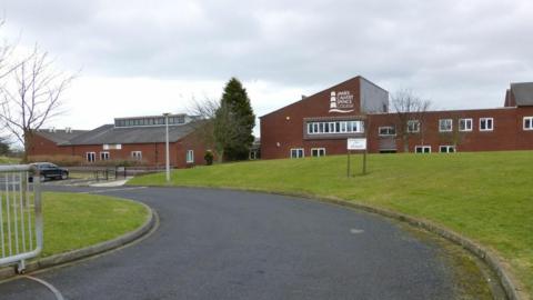 The outside of James Calvert Spence College, which is a brick building with a grassy bank in front of it.