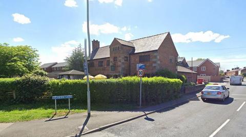 Blue Dunkirk Lane road sign shown in front of a hedge and road 30 mph speed limit sign at the front of the Dunkirk Hall pub in Leyland on a sunny day.