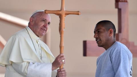 Pope Francis receives a cross made by an inmate during his visit to a penitentiary in Ciudad Juarez