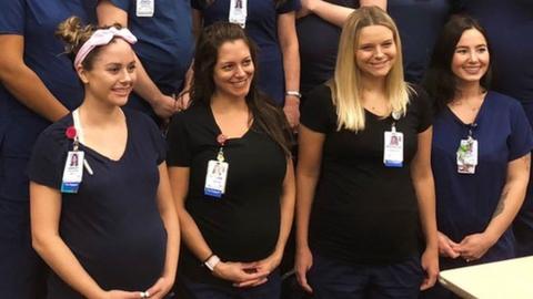 12 of the 16 pregnant nurses pose with their bumps on show in uniform