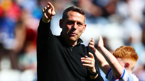 Reading FC boss Leam Richardson points ahead, wearing black fleece