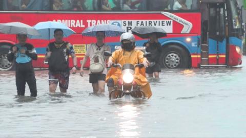 People drive and motorcycle through knee-deep water