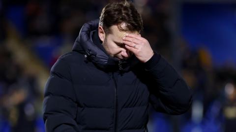Tom Cleverley looks down with his hand on his forehead after being sent off