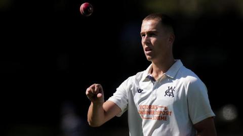 Pace bowler Mitch Perry tosses a ball up in the air as he walks back to his mark.