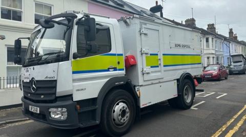 A bomb squad van on a street of terraced houses