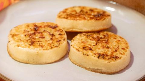Three cooked, buttered crumpets on a white plate