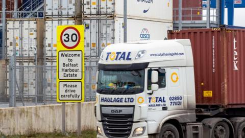 Haulage lorry drives passed a welcome sign to Belfast Harbour Estate in the Port of Belfast. 