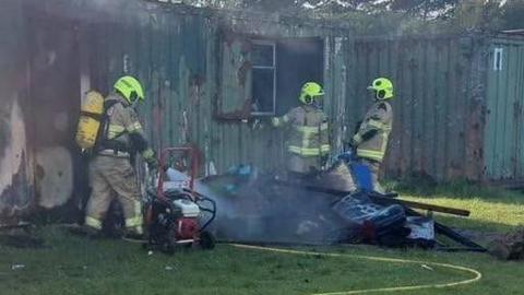 Firefighters tackling a blaze at some metal containers at Trimsaran rugby club.