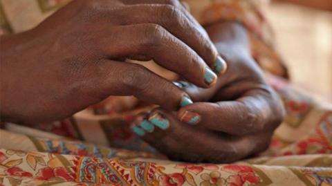 Close up of a woman's hands, with chipped blue nail polish.