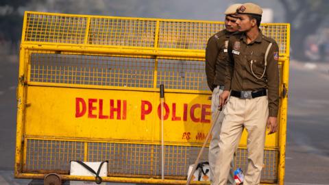 Two security personnel stand guard next to a yellow railing that says 'Delhi police' near the site of the explosion, taken on Tuesday.