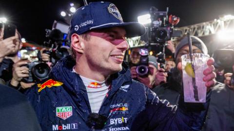 Max Verstappen holds up a drink in celebration after winning the 2024 F1 drivers' championship at the Las Vegas Grand Prix