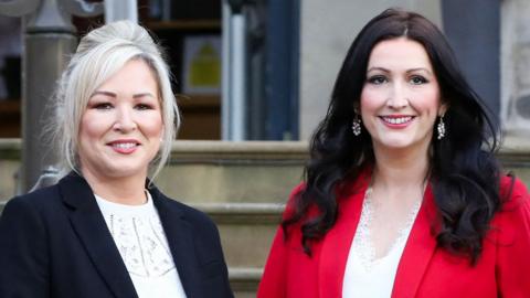 Michelle O'Neill and Emma Little-Pengelly smile on the steps in front of Stormont castle