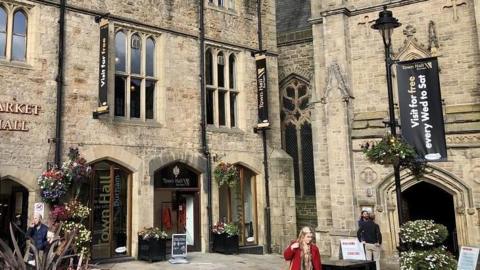 The entrance to Durham Town Hall is in the corner of a grand white stone building. The windows and entrances are shaped like arches.