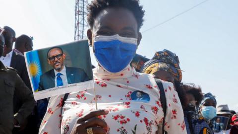 People hold flags with the pictures Rwandan President Paul Kagame, during an armed forces day celebration in Pemba, Mozambique - September 2021