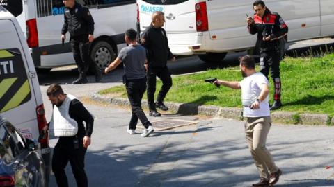 A man holds a gun, after gunfire was heard near the building housing the Israeli consulate, according to a witness, in Istanbul, Turkey