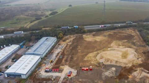 Aerial view of the new depot site with vehicles and containers in view, alongside existing industrial buildings.