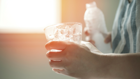 Anonymous hands holding a glass and bottle of water