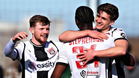 Flint's Elliot Reeves hugs smiling team-mates in celebration after scoring his second goal in the semi-final