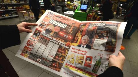 A woman reads an article in the "Blesk" Czech tabloid newspaper with images of the Minister of Health of the Czech Republic Roman Prymula allegedly dining at a restaurant despite Covid-19 restrictions in Prague, on October 23, 2020.