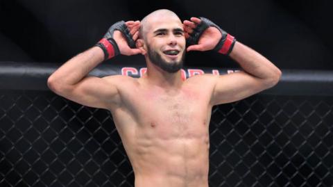 Muhammad Mokaev puts his hands to his ears in the octagon