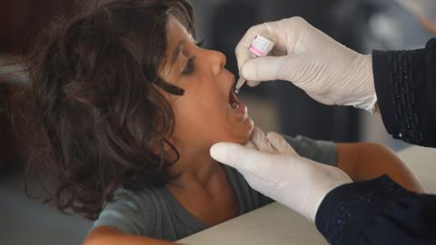 A health care worker administers an oral polio vaccine to a child in Gaza