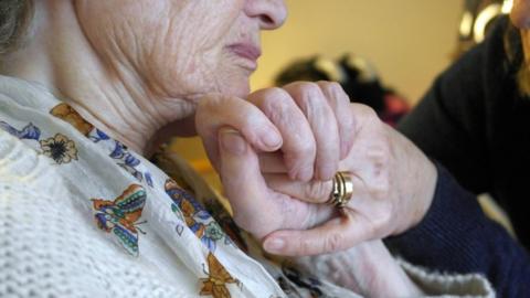 Woman holding hands with a carer (generic)