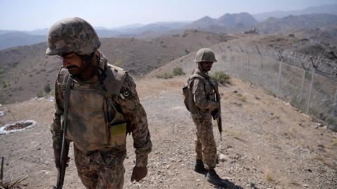 Pakistani soldiers patrol next to a newly fenced border fencing along Afghan border at Kitton Orchard Post in Pakistan's North Waziristan on 18 October 2017.