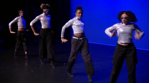 Black ballet dancers performing in black trousers and silver tops