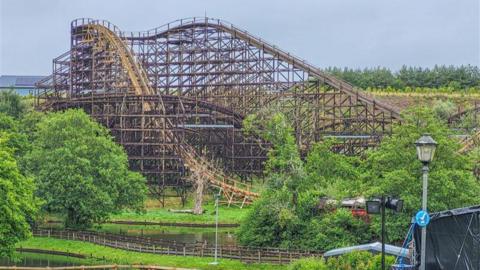 The wooden rollercoaster Megafobia. It has a steep climb and a dramatic drop, and is built from wooden scaffolding. Trees can be seen in the foreground.